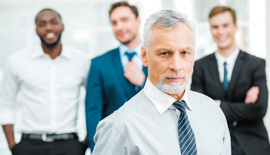 Older man standing in front of 3 younger workers
