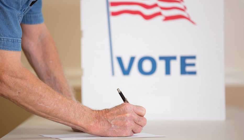 a man casts his vote in front of a booth marked vote