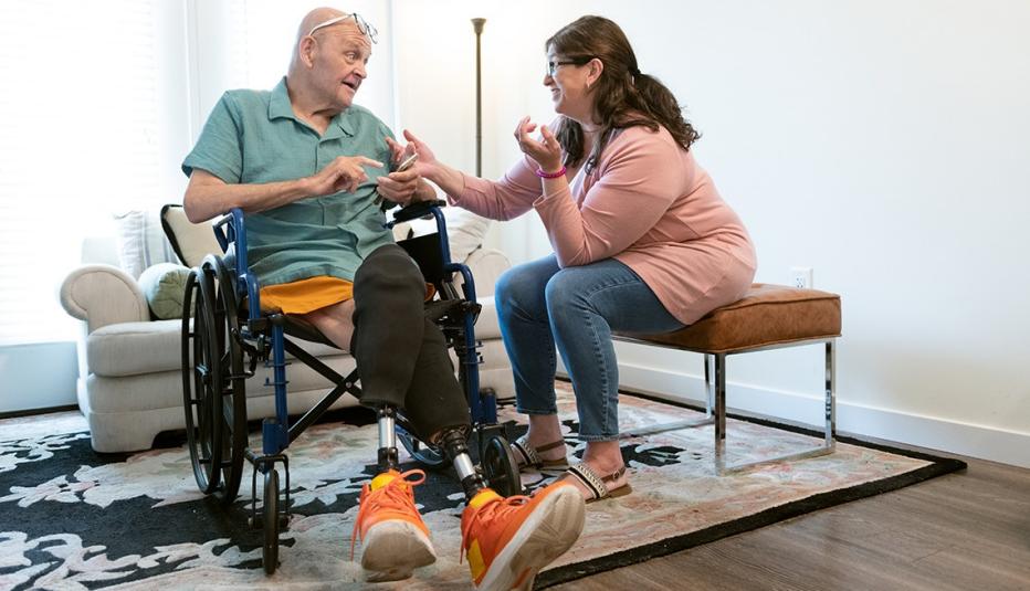 A senior man with amputations gets help from a nurse at home