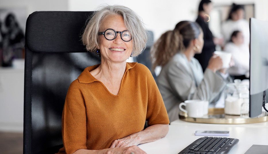 smiling older woman sitting at table with black computer keyboard 
