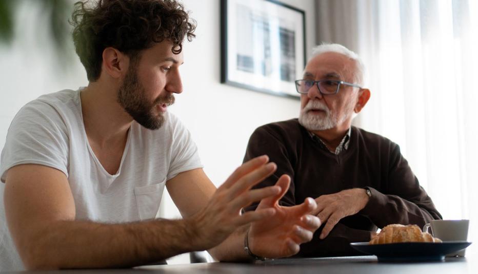 Worried 70-year-old man is talking with his son in the living room.