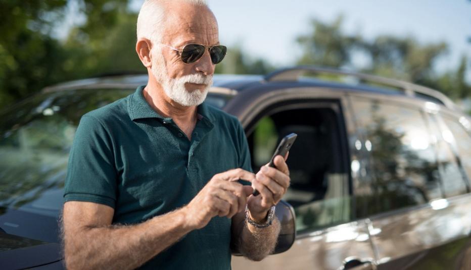 Senior man leaning on his car and texting a message. Senior man leaning on his car and texting a message.