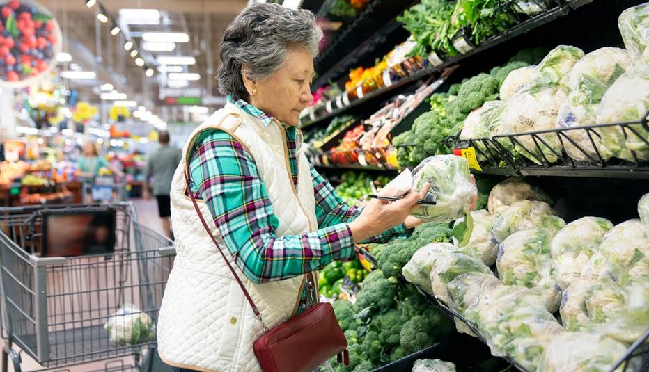 Senior woman carefully selects fruits and vegetables at grocery store