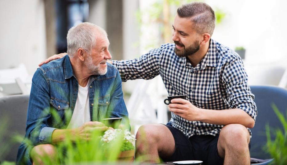 An adult son sits with his older father at a coffee shop