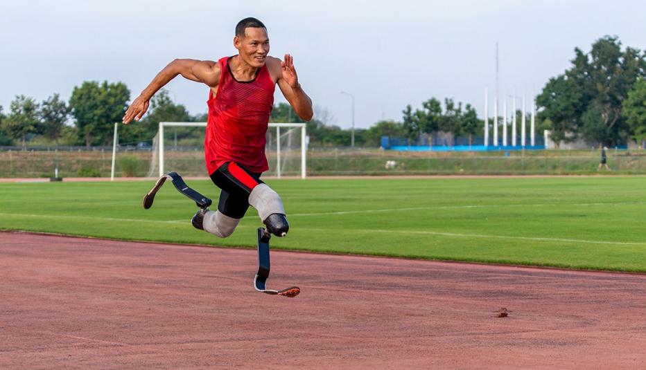 Man with prosthetic legs running on a dirt track.