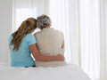 View from behind of a mother and daughter embracing on a bed