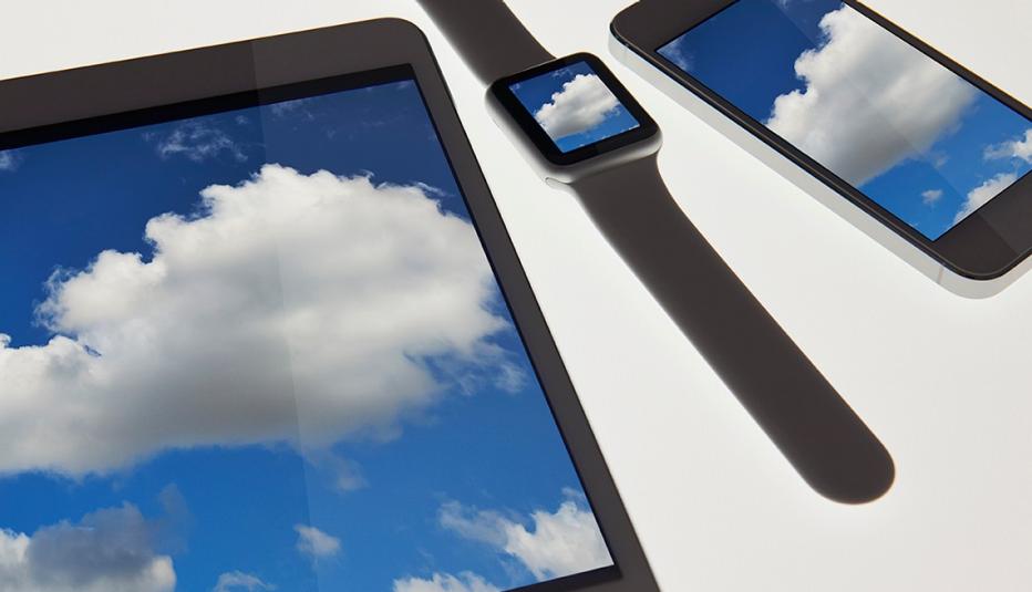 Close-up of technology devices with touchscreens reflecting a blue sky with clouds.