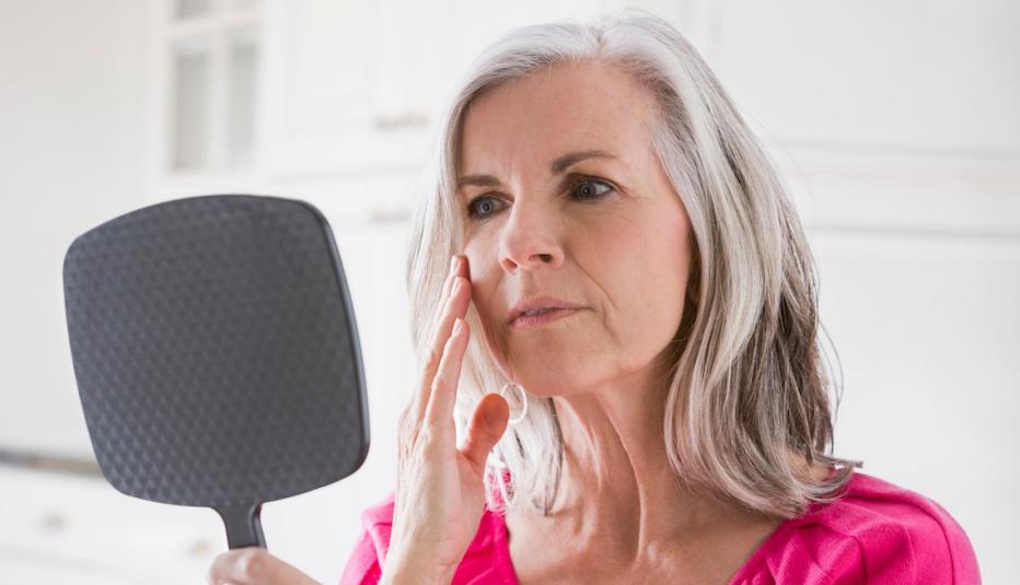 Caucasian woman looking at skin in mirror