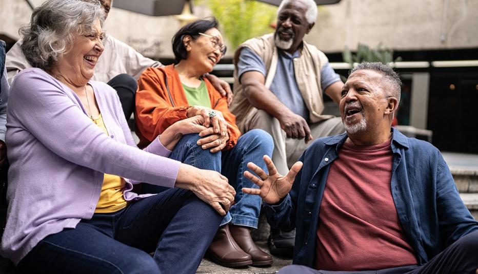 A group of senior friends are talking and laughing outdoors.