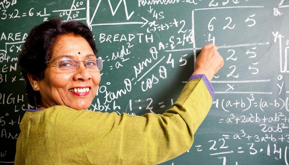 smiling teacher writing on blackboard