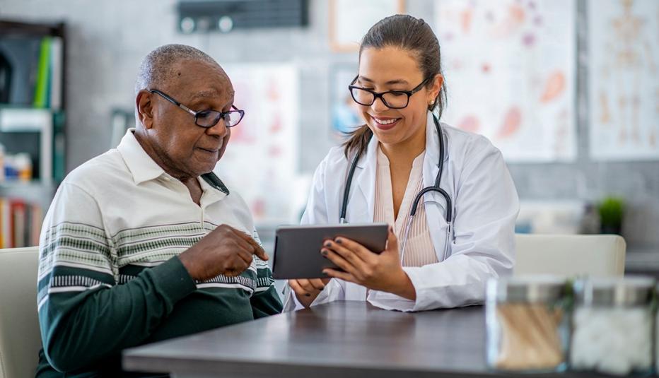 A man in his doctor's office as doctor shows him something on a digital tablet
