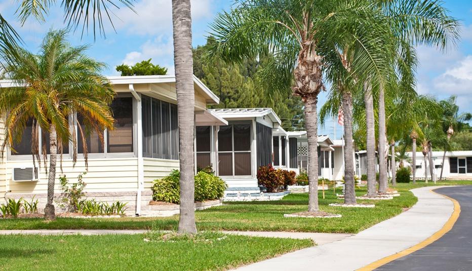 Mobile homes in a row located in a mobile home park in the tropics. Street view with palm trees and sidewalk