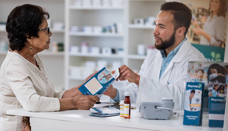 Pharmacist gives senior woman brochure at pharmacy checkout