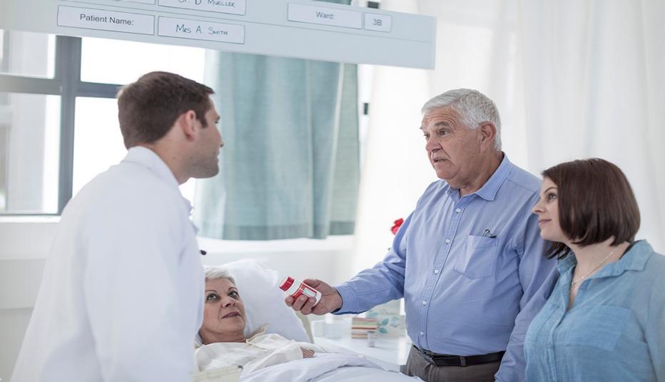family and doctor around woman in hospital bed