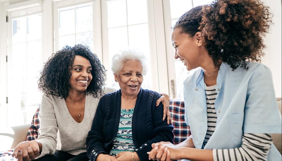 two younger women talking with older woman on a couch