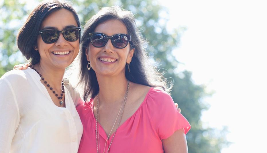 Smiling mother and daughter posing outdoors wearing sunglasses Smiling mother and daughter posing outdoors wearing sunglasses