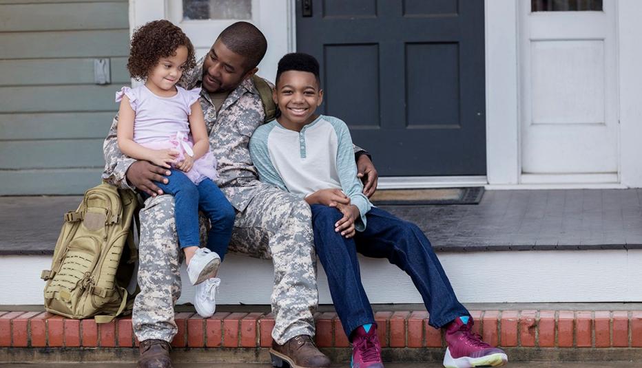 Army dad sits on the porch with his young son and daughter