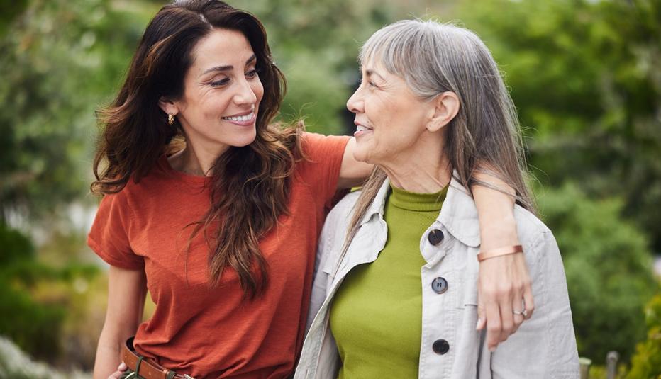 Mother and Daughter Woman standing arm in arm with her senior mother and smiling while standing together outside in a yard at home.