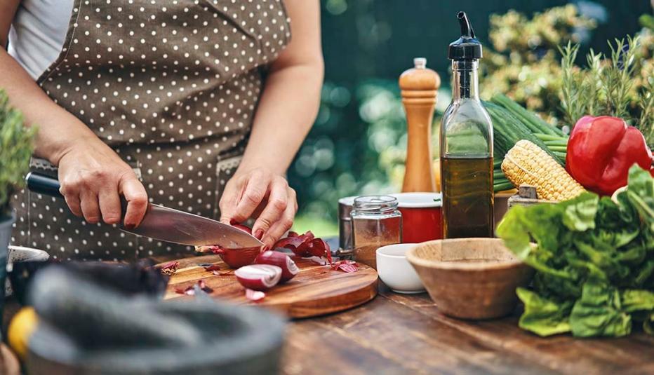 Person cutting onions on a wooden cutting board