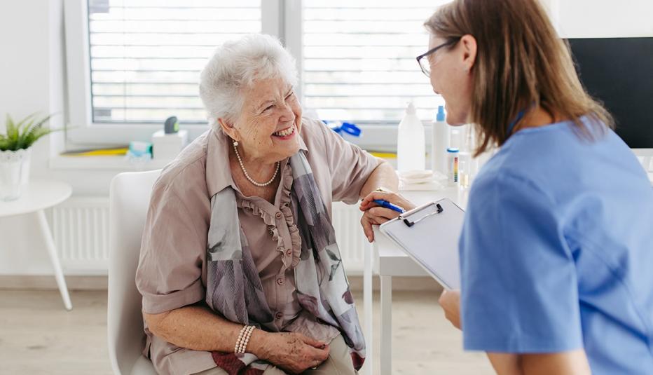 Older woman with short white hair talks with a young doctor holding a clipboard