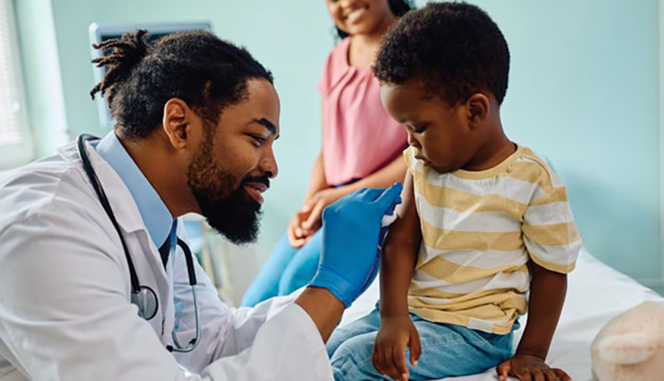 male doctor preparing a small boy&rsquo;s arm for a vaccination