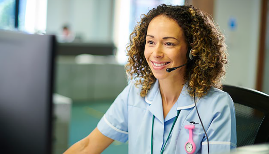 smiling woman looking at computer screen with headset on