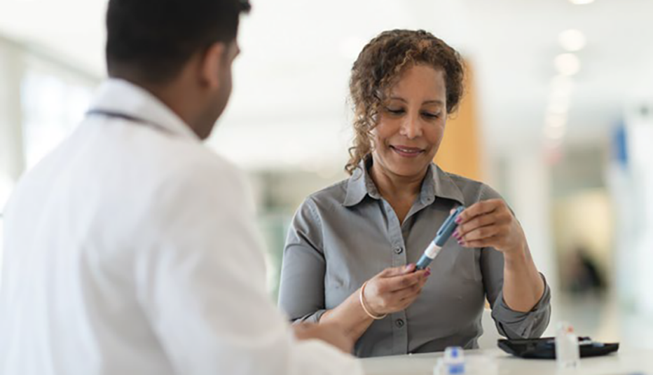 doctor, facing away from camera, looking at a patient examining an insulin pen