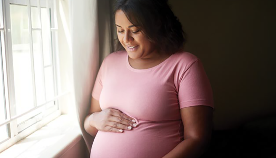 smiling pregnant woman with hand on her belly, looking down