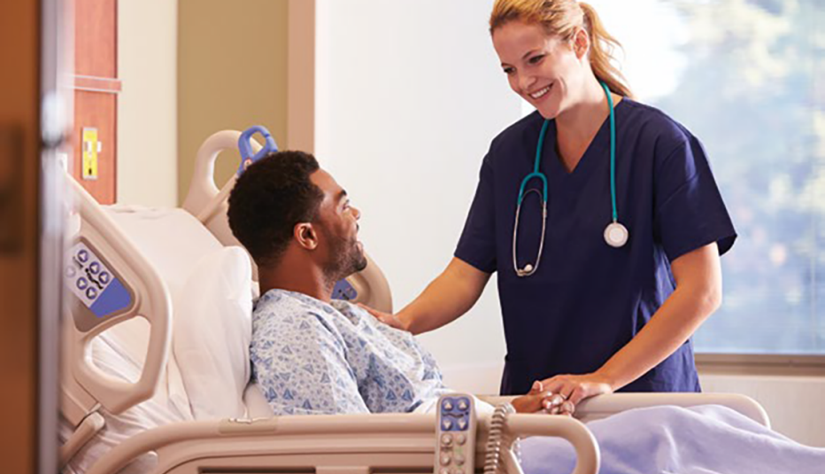 smiling woman doctor facing man in hospital bed with her hand on his shoulder