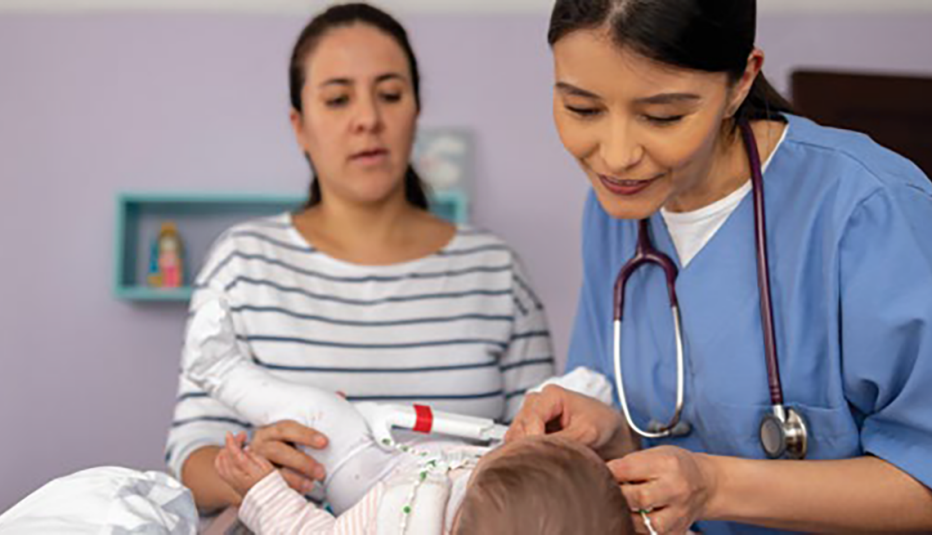 young female doctor examining a small child on exam table as mother looks on