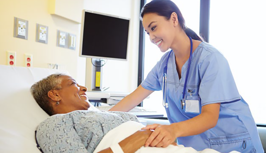 smiling doctor leaning over patient in hospital bed