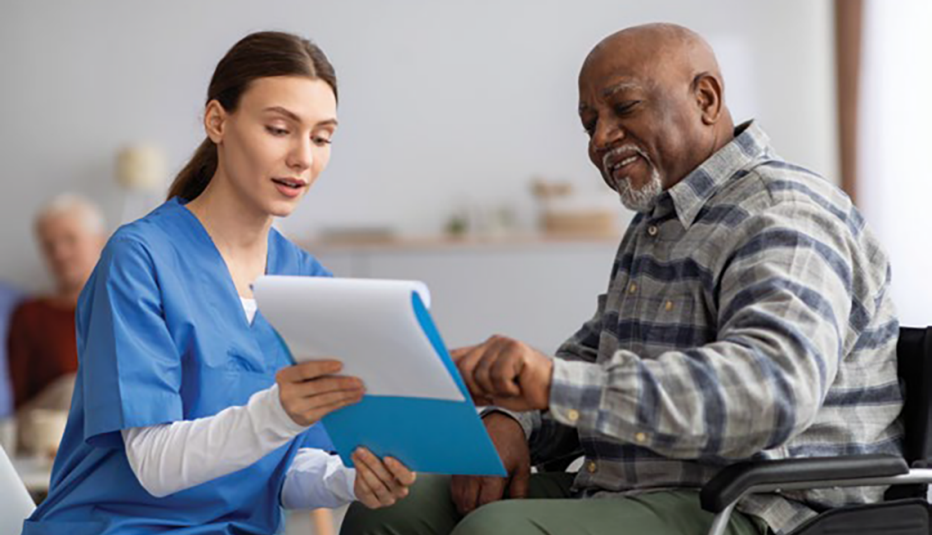 1368989606 nurse showing man in wheelchair a paper