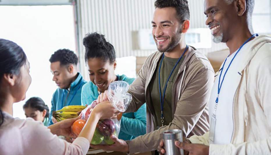 968605886 smiling workers at food bank giving food to customers