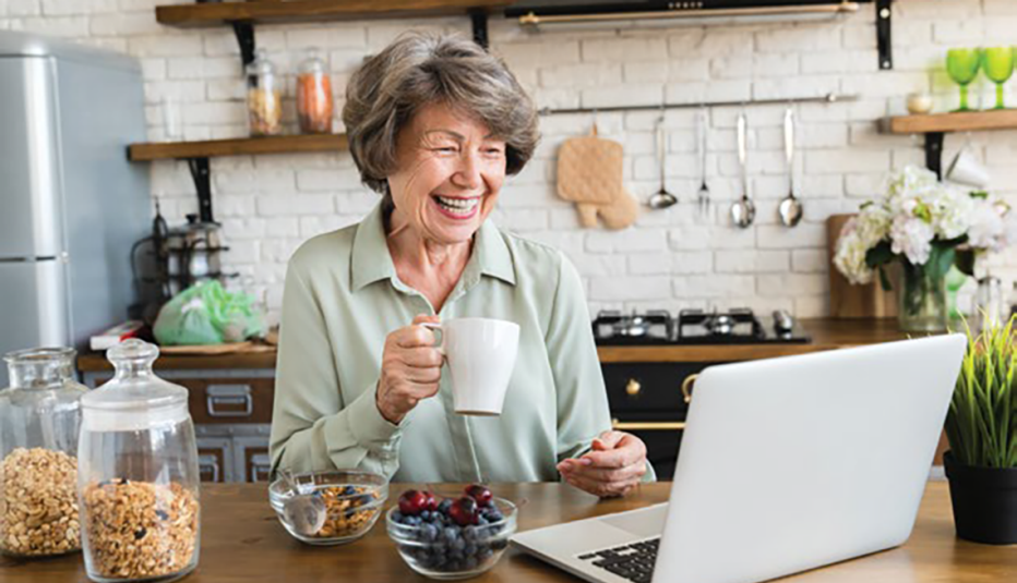 2030584711 woman watching movie on laptop drinking from a cup