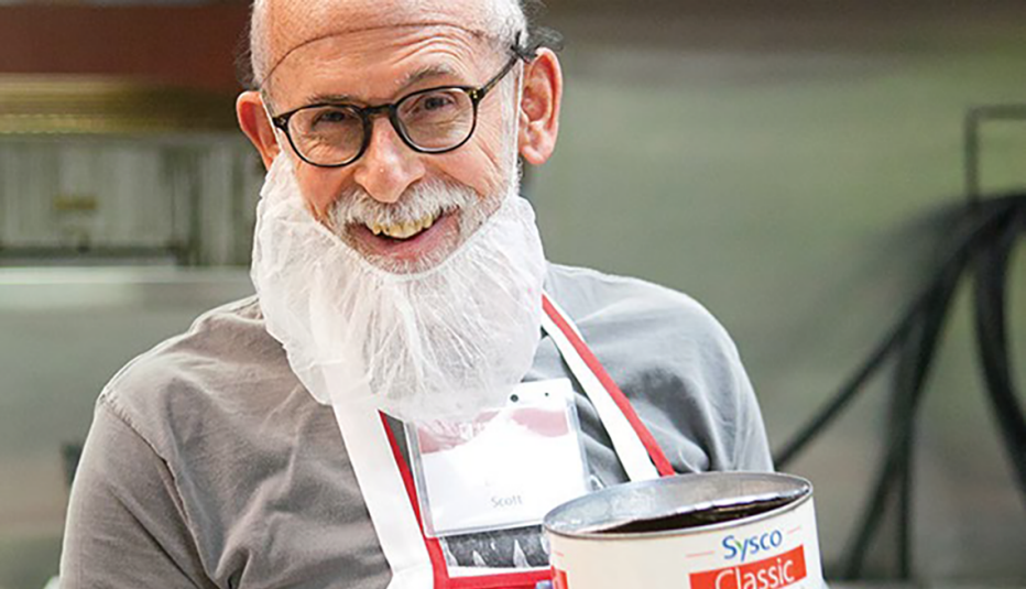 smiling worker with large open can with Sysco Classic on label