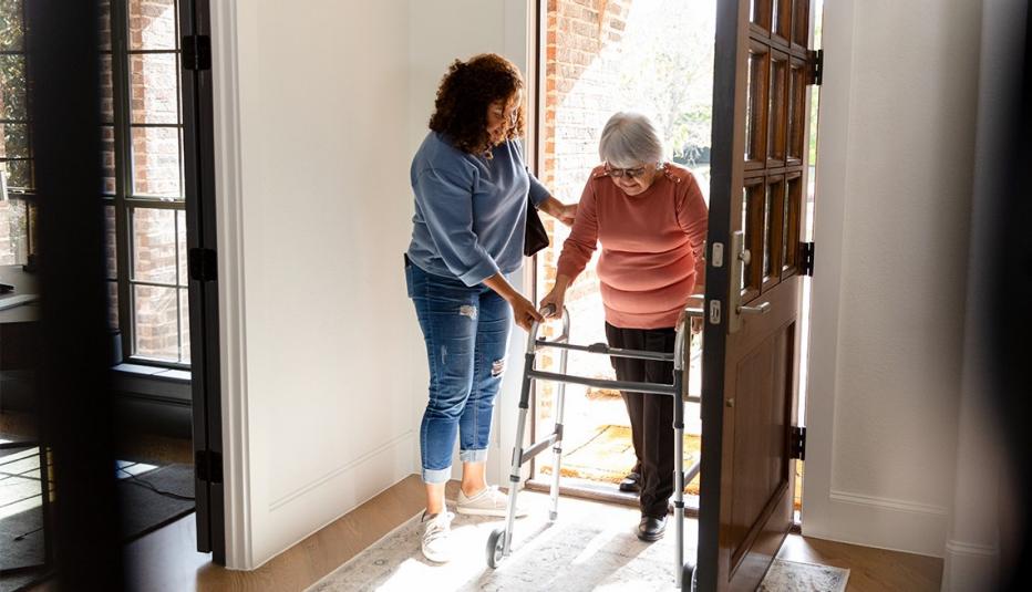 Medicaid Provides Critical Health Care Coverage to Family Caregivers A healthcare worker helps an elderly woman walk using a rollator. Indoors, home setting