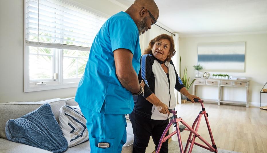 Male caregiver assisting senior woman with mobility walker at home