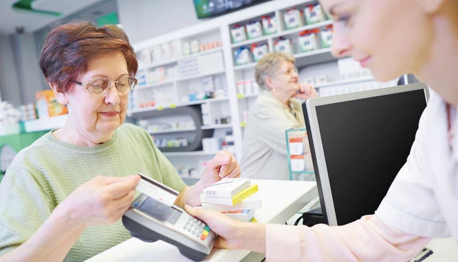 Most Medicare Part D enrollees who reach the new $2,000 out-of-pocket spending cap will see substantial savings despite premium changes Senior customer paying by credit card at drug store