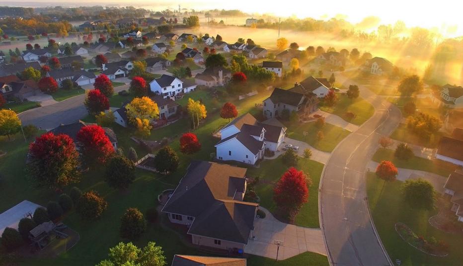 Illustration of a neighborhood from the air, with streets and houses. The sun is just peeking over the horizon.