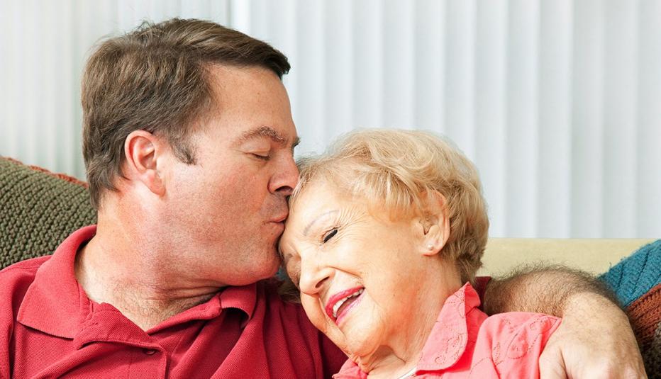 Woman gets a kiss on the forehead from her loving adult son