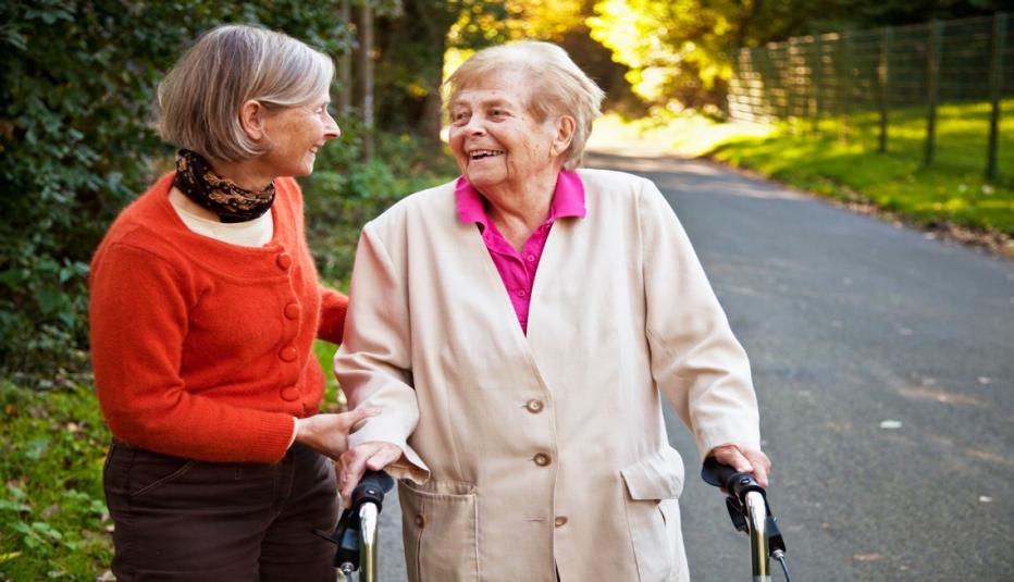 elderly woman walking with her walker outdoors, with her daughter