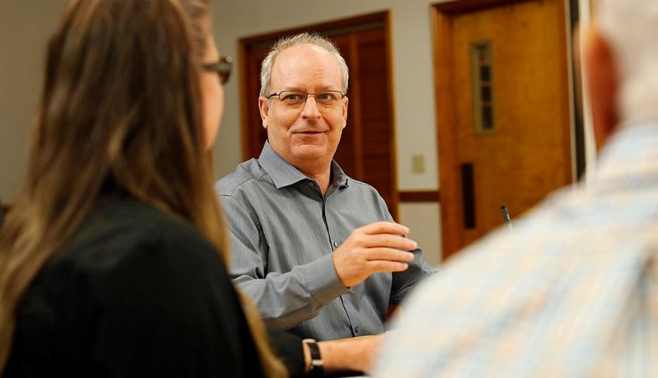 Scott Miller talks with coworkers during a meeting.