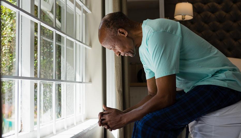 Older African American man sitting by window in bedroom