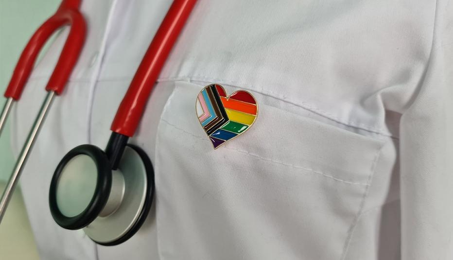 Silhouette of doctor in white coat with stethoscope and LGBT badge on pocket