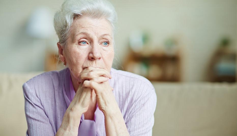 Woman with hands clasped by chin looking worried Woman with hands clasped by chin looking worried