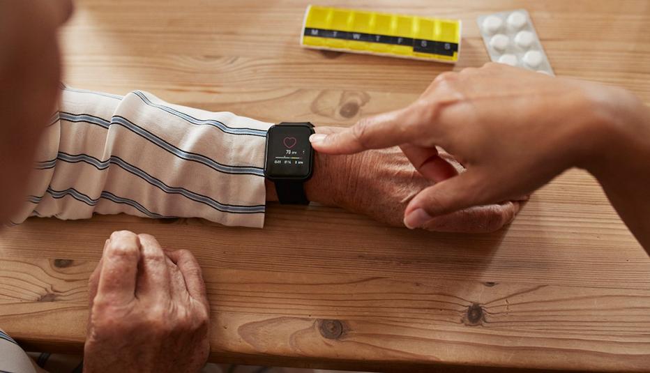 High angle view of female nurse checking heart rate of senior woman using a smart watch.