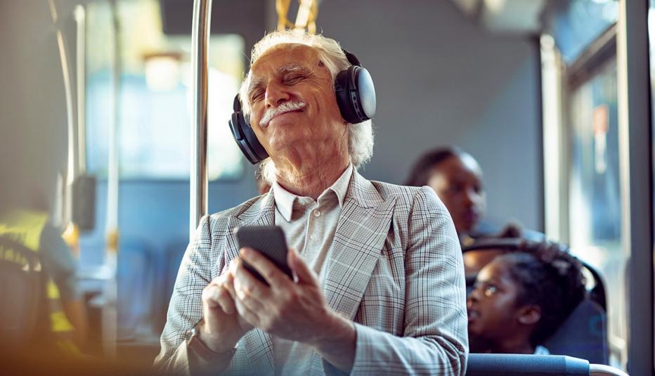 Close up of a senior man listening to music on his phone while commuting in a bus.