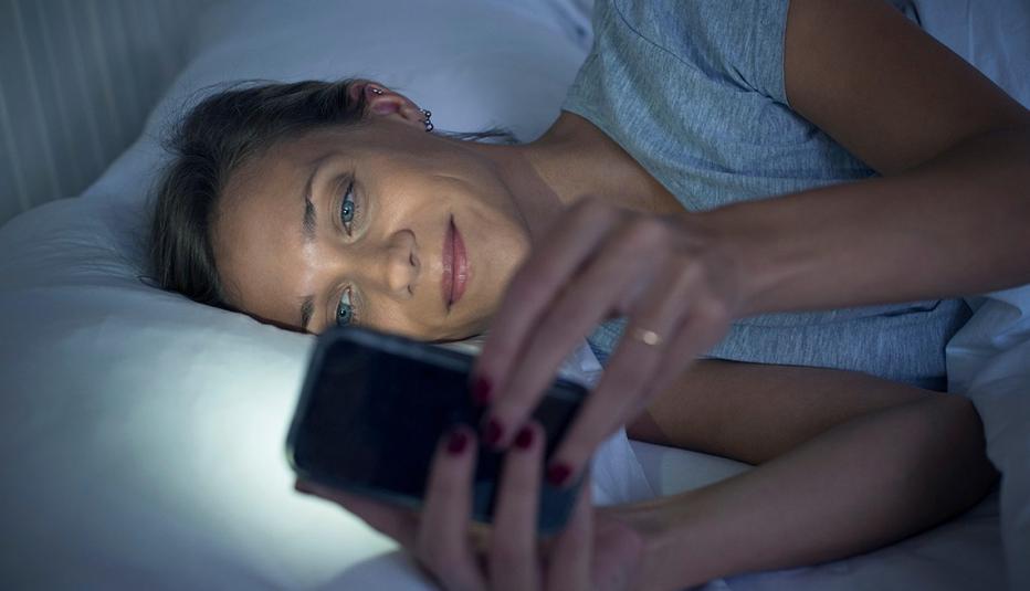 Woman in bed using smartphone
