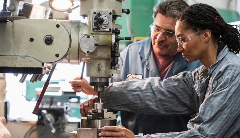 Workers using drill press in factory - stock photo
