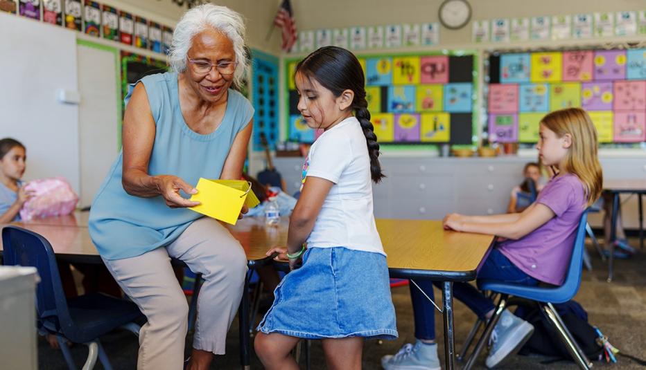 A kind and patient senior adult female teacher of Pacific Islander descent uses flashcards while providing one on one assistance with a female elementary age student during class.